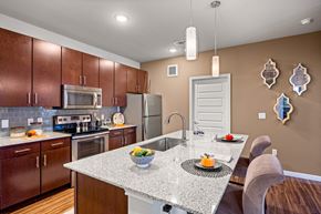 Austin apartment for rent - A kitchen with brown cabinets and a granite countertop. at Bridge at Southpark Meadows, Texas, 78748