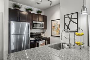 Austin apartment for rent - A kitchen with a stainless steel refrigerator and a granite countertop. at The James on South First, Austin, TX, 78748