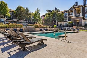 Austin apartment for rent - A pool surrounded by lounge chairs and trees. at Preserve at Rolling Oaks, Austin, 78728