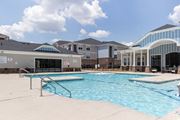 Spartanburg apartment for rent - A swimming pool in front of a building with a glass wall.