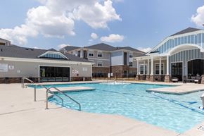 Spartanburg apartment for rent - A swimming pool in front of a building with a glass wall.