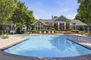 Durham apartment for rent - A large swimming pool in front of a building with a poolside lounge.