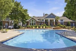 Durham apartment for rent - A large swimming pool in front of a building with a poolside lounge.