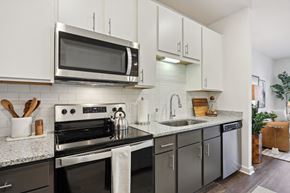 Cartersville apartment for rent - A modern kitchen with a black stove top oven and a microwave above it. at Arcadia Cartersville Apartments, Cartersville, GA, 30121