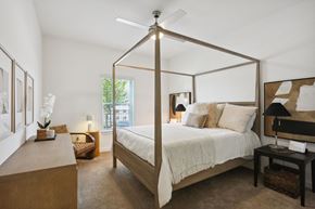 Cartersville apartment for rent - A bedroom with a four poster bed and a table with a lamp on it at Arcadia Cartersville Apartments, Georgia