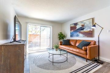Little Rock apartment for rent - A living room with a brown couch, a glass coffee table, and a painting on the wall.