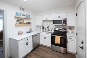 Memphis apartment for rent - A kitchen with white cabinets and a black stove top oven. at Century Apartments, Memphis, 38117