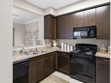 Hardeeville apartment for rent - A kitchen with brown cabinets and black appliances.