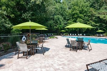 A patio with tables and umbrellas next to a swimming pool