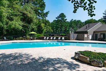 A swimming pool with a house and trees in the background