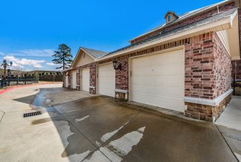 A white garage door on a brick building with a driveway