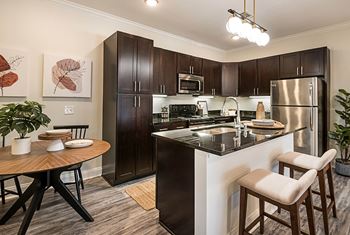Spacious kitchen with stainless steel appliances and a breakfast bar with a wooden table and chairs