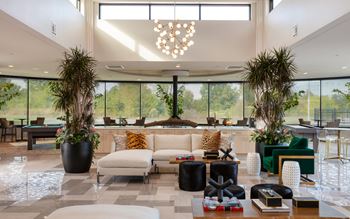 The lobby of a hotel with a couch and chairs and large windows