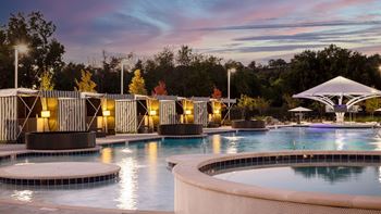 A swimming pool at night with a sunset in the background