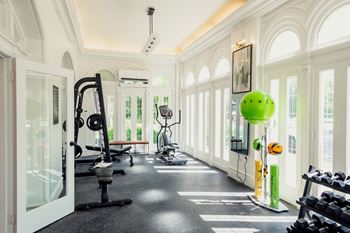 A gym with a variety of equipment including a treadmill, weights and a bench.