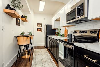 A kitchen with black appliances and white cabinets.