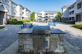 An outdoor kitchen with a grill in front of an apartment building