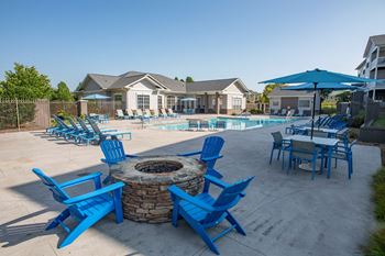 Our apartments have a pool and patio with blue chairs and umbrellas