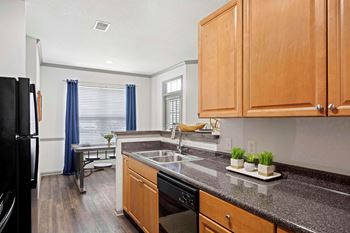 A kitchen with wooden cabinets and a black refrigerator.