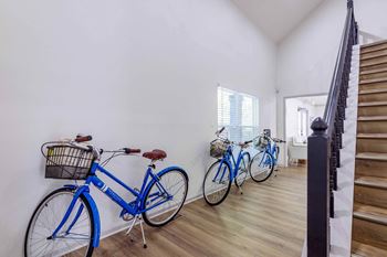 Three bikes are lined up against a wall in a room with stairs