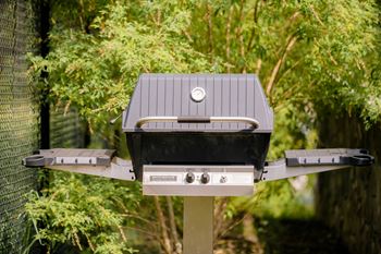 A barbecue grill with a tin roof on a pole