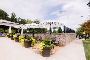 A patio with chairs and umbrellas and a stone wall