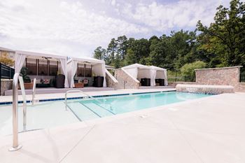 A swimming pool in front of a pool house with tents