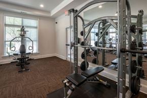 Arlington apartment for rent - A gym with a squat rack, bench, and weights. at Hall Creek Apartment Homes, Arlington