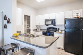 Cordova apartment for rent - a kitchen with white cabinets and black appliances at Lincoln at Wolfchase, Cordova