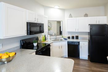 A kitchen with black appliances and white cabinets.