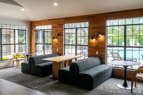 Overland Park apartment for rent - A black couch and chair are in a room with a wooden floor and a pool outside the window.