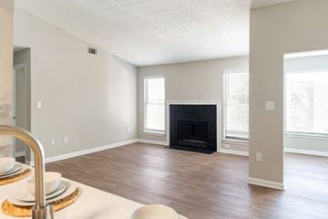 Alpharetta apartment for rent - A modern living room with a fireplace and a dining table set for two.