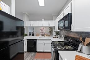 Houston apartment for rent - Modern kitchen with black appliances and white cabinets at The Ambrose, Texas, 77040