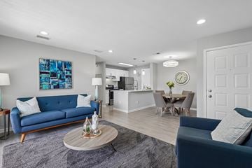 Doraville apartment for rent - A blue sofa sits in a well-lit living room with a dining area in the background.