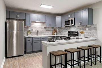 Roswell apartment for rent - A kitchen with a stainless steel refrigerator and wooden bar stools.