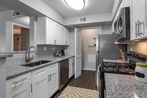 Louisville apartment for rent - A kitchen with white cabinets and a black refrigerator.