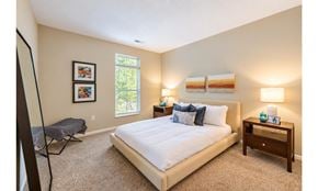 Columbus townhouse for rent - A bedroom with a large bed, a window, and a nightstand with a lamp.
