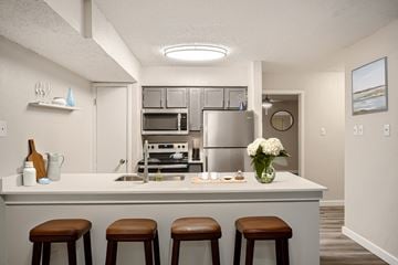 Irving townhouse for rent - A kitchen with a white counter and brown stools.
