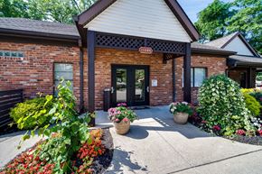 Cincinnati apartment for rent - A building with a red brick facade and a sign that reads "TESDA" is surrounded by a variety of potted plants and flowers.