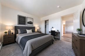 Lansdale apartment for rent - A bedroom with a large bed, a desk with a chair, and a mirror on the wall.