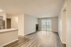 Irving townhouse for rent - A spacious room with wooden flooring and white walls.