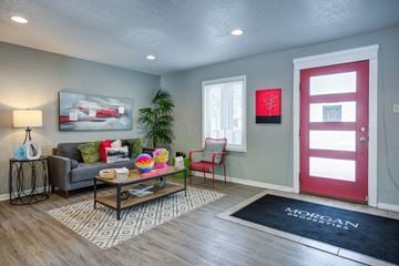 Indianapolis apartment for rent - A living room with a grey couch, a coffee table, a red door, and a painting on the wall.