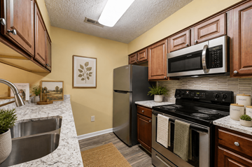 Fayetteville apartment for rent - A kitchen with a black stove top oven and a black microwave above it.