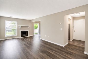 Indianapolis townhouse for rent - A large empty room with a fireplace and wooden floors.