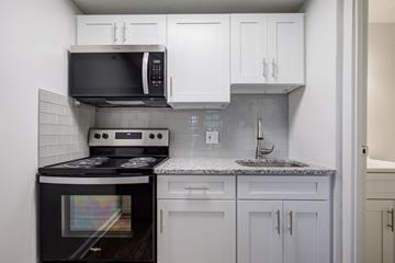 Rosedale apartment for rent - A kitchen with a black stove top oven and white cabinets.