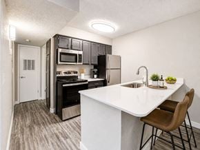Oklahoma City apartment for rent - A modern kitchen with a white countertop and brown chairs.