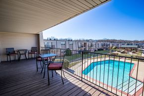Bethany apartment for rent - A wooden deck with a table and chairs overlooking a pool.
