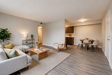 Bethany apartment for rent - A living room with a grey couch, a wooden coffee table, and a dining table with chairs.