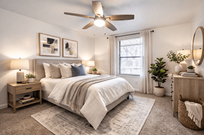 Hilliard apartment for rent - A bedroom with a large bed, a ceiling fan, and a window with white curtains.