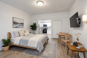 Louisville apartment for rent - A bedroom with a bed, a table, and a television.